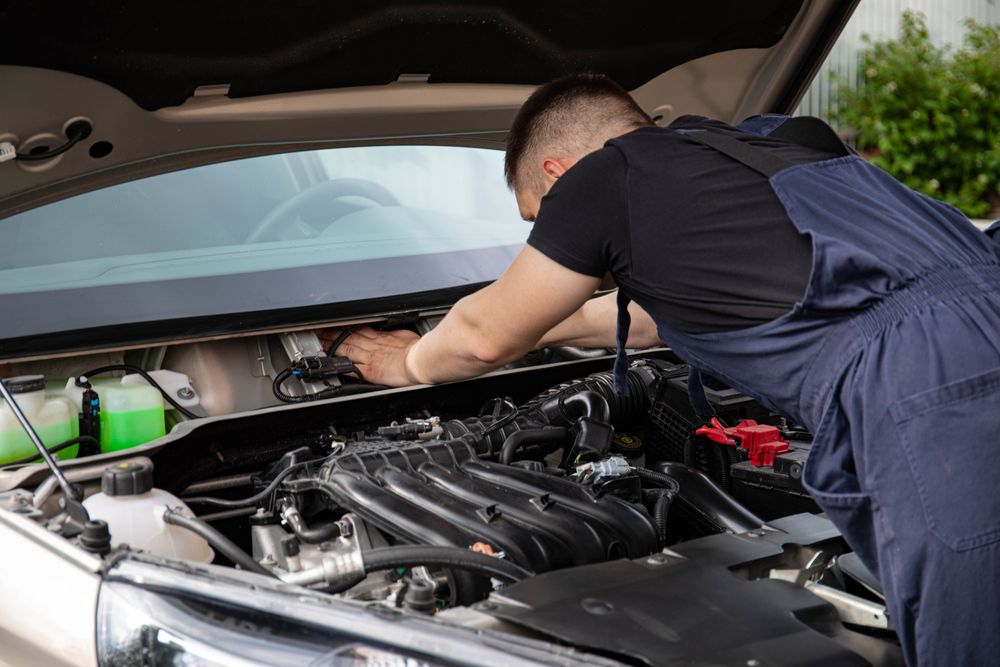 Mechanic working under the hood of a car in a service bay